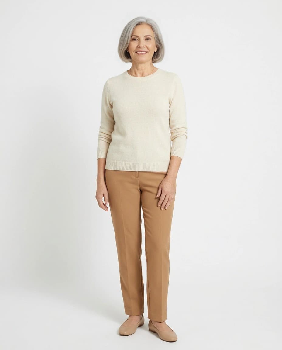 Modelo sintética de 60 ou mais com blusa de tricô creme, calça de alfaiataria e mocassim