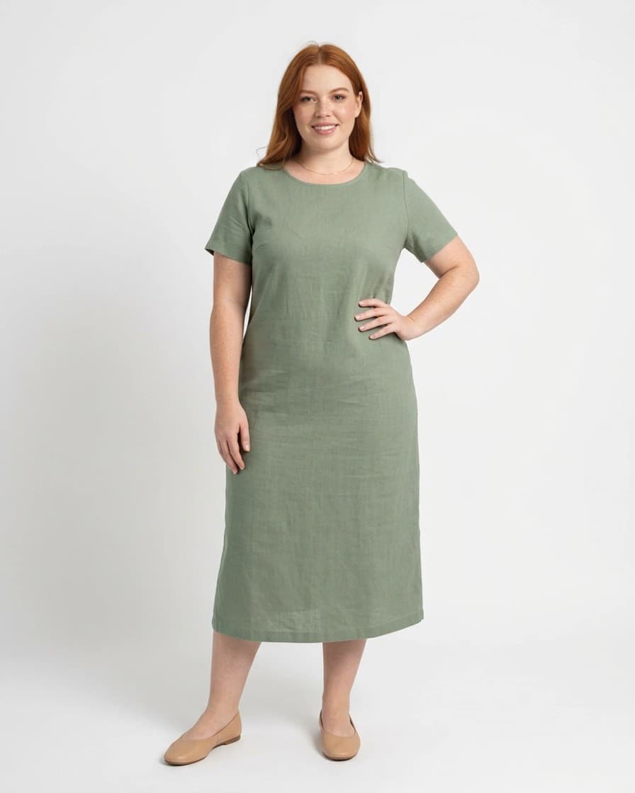 Modelo sintética adulta plus size com a mão na cintura, vestido verde sálvia e sapatilha