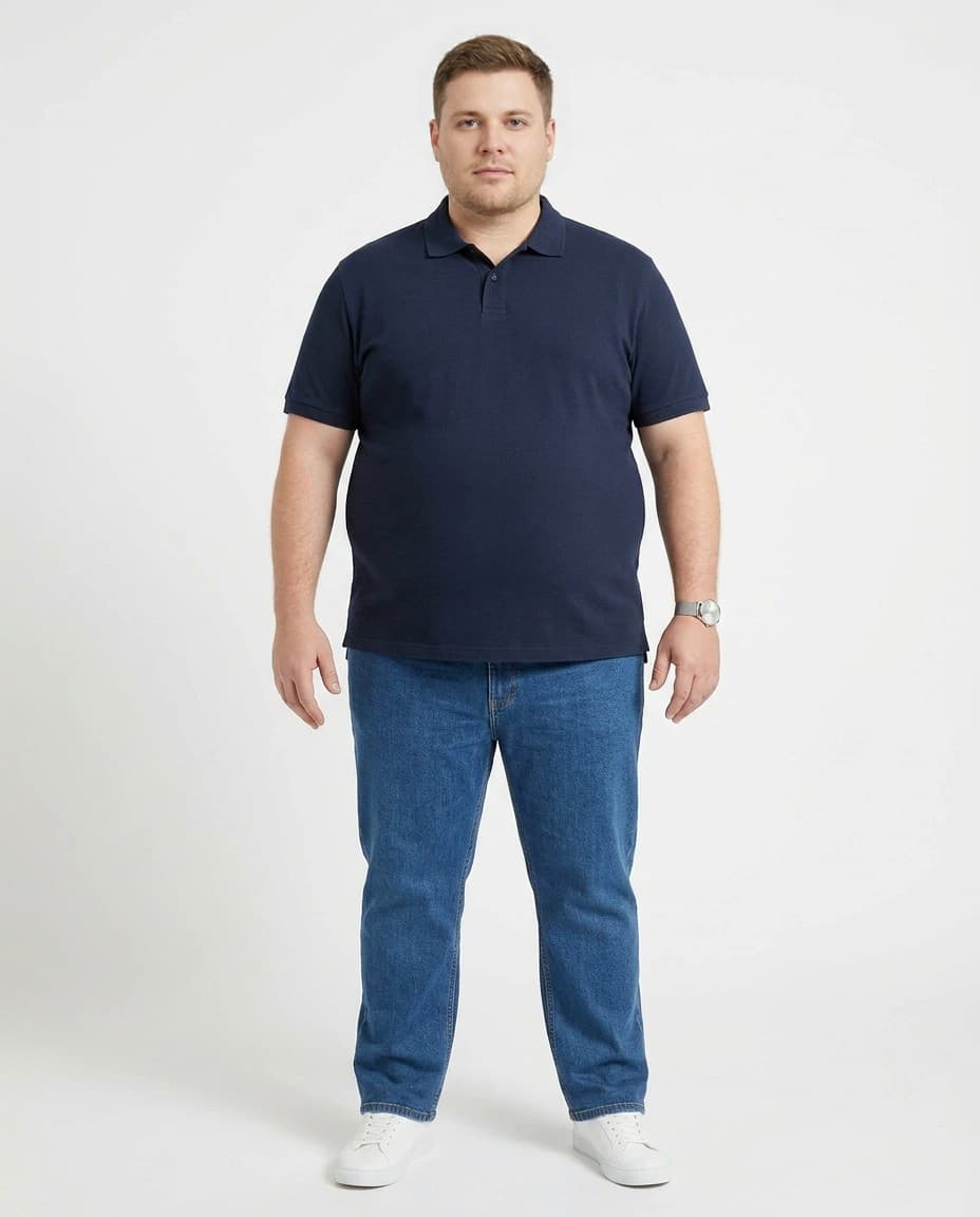 Modelo sintético adulto plus size de frente, com camisa polo azul-marinho, jeans e tênis branco